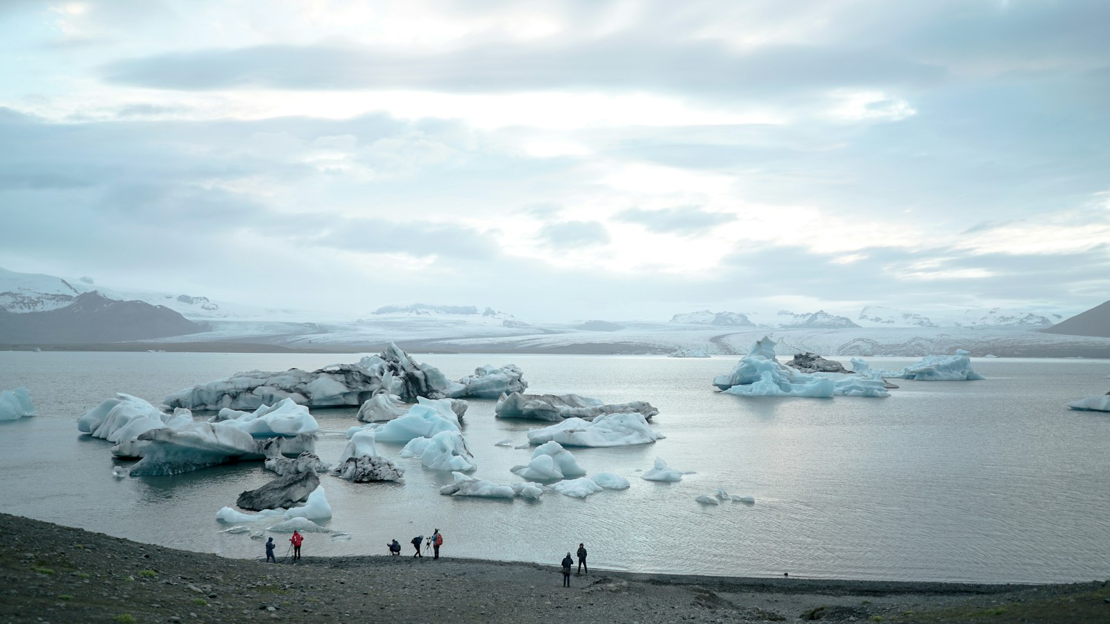 People standing on the shore of a glacier lagoon