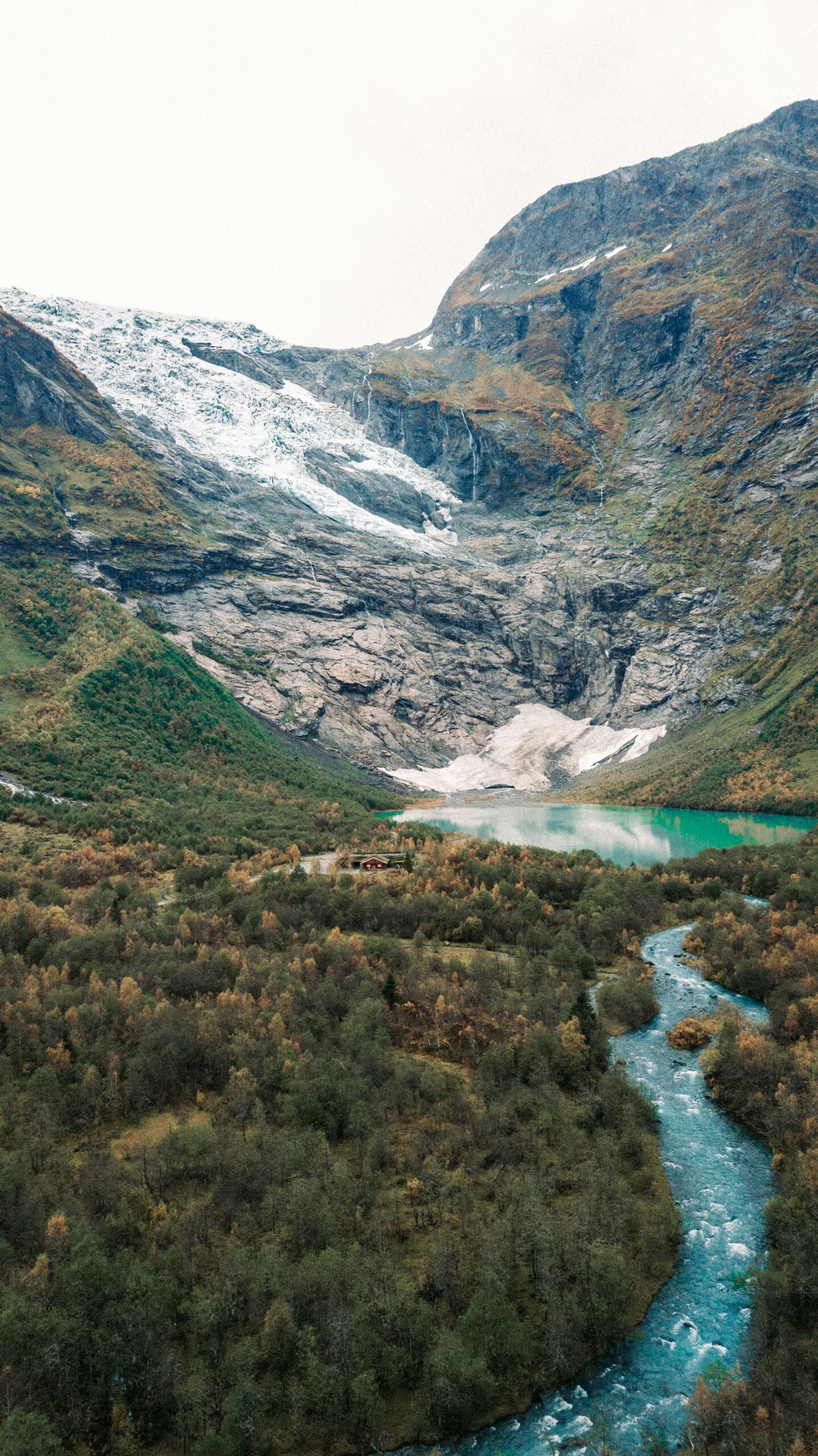 A glacier feeding a river through a forested valley
